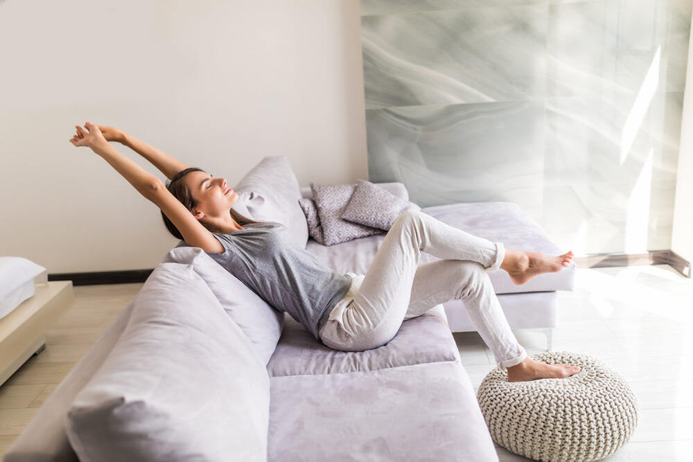 souriante-jeune-femme-se-detendre-allonge-sur-le-canape